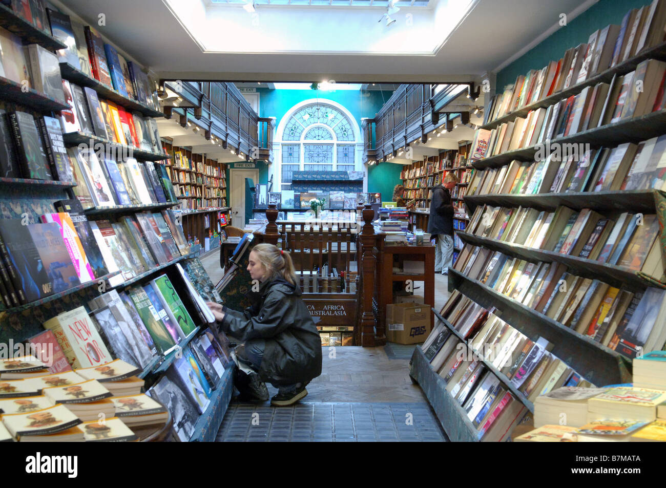 Una donna scegliendo un libro per comprare e leggere libri Daunt a Londra. Foto Stock