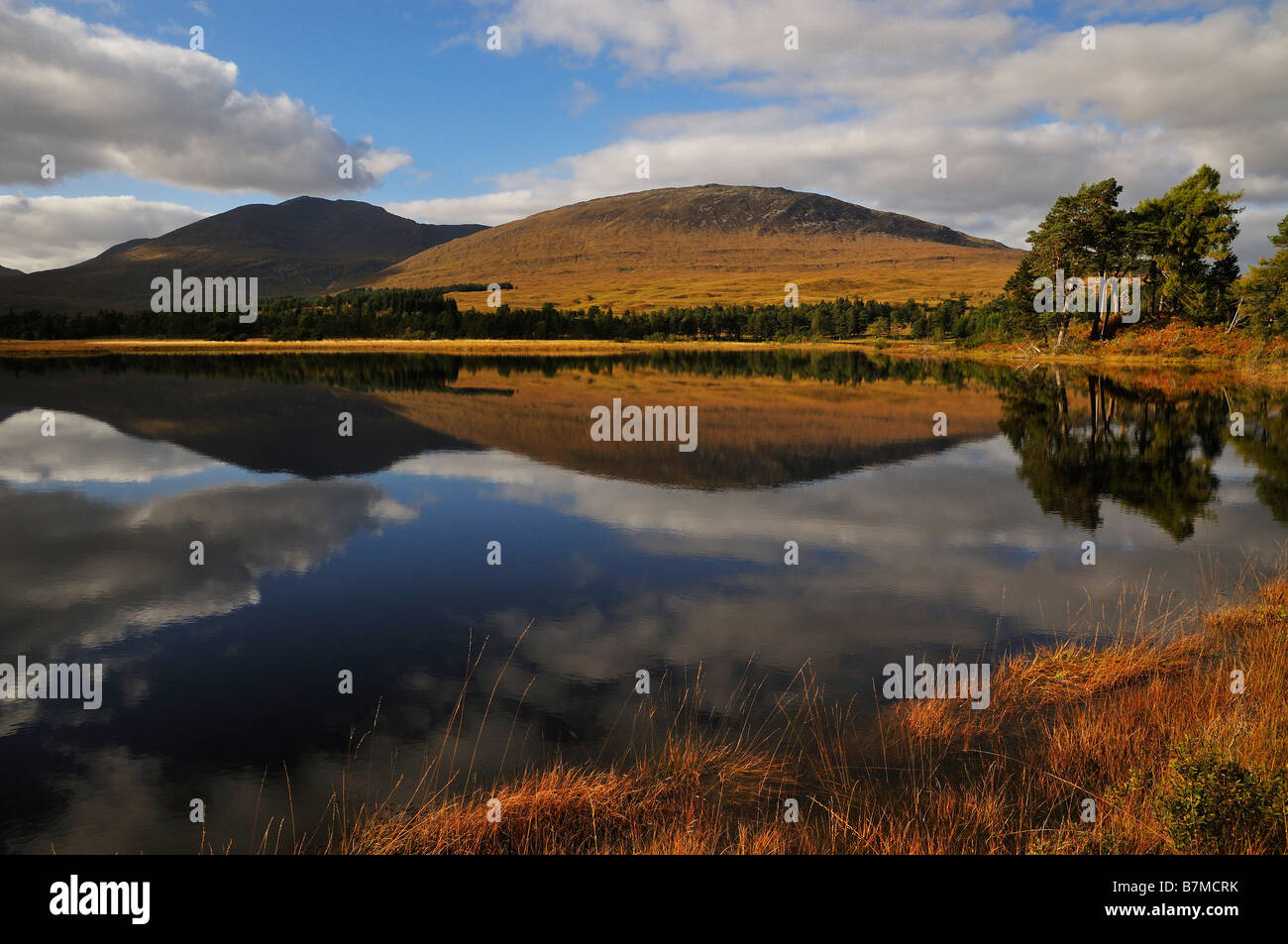 Colline alberi e nuvole riflettono in Loch Tulla Rannoch Moor Highlands scozzesi UK Foto Stock