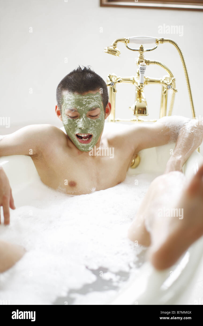 L'uomo rilassante in una vasca con una maschera per il viso Foto Stock