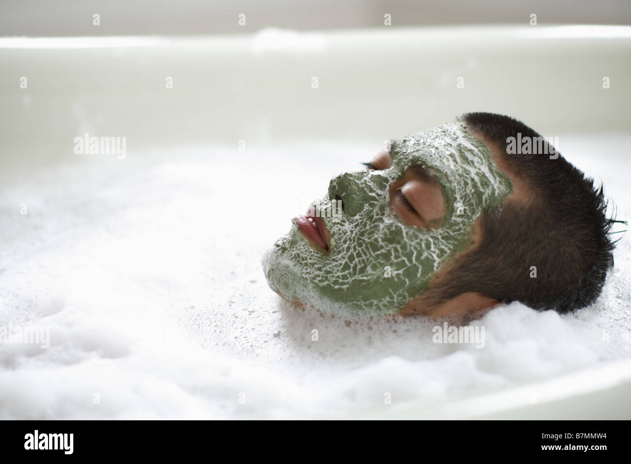 Uomo con maschera facciale giacente nel bagno di schiuma Foto Stock