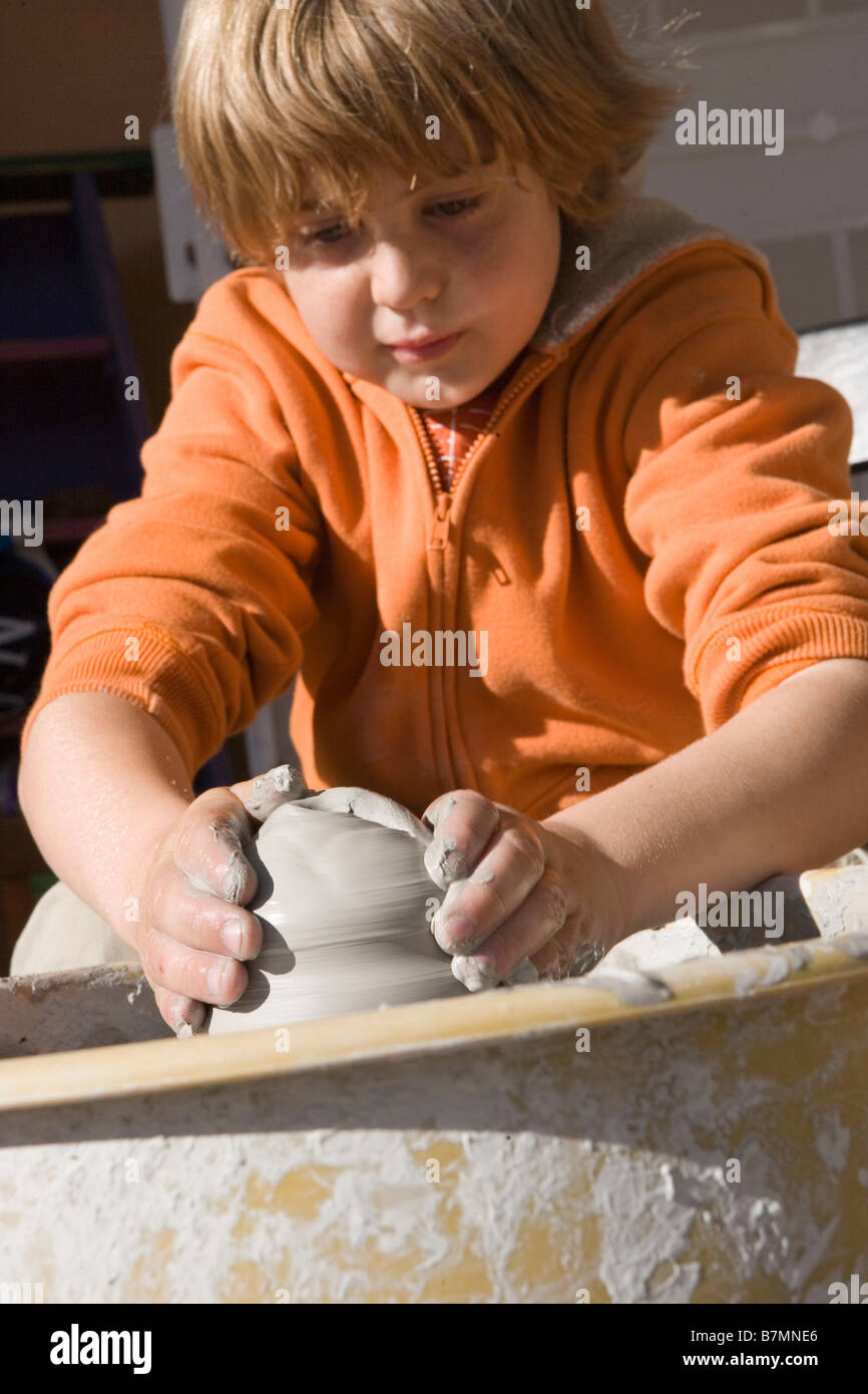 Bambino di nove anni lavora su un vaso utilizzando una ruota Foto Stock