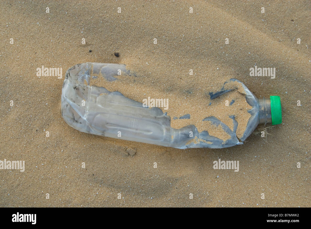 Un vuoto in plastica fracassato di acqua in bottiglia in una spiaggia sabbiosa Foto Stock