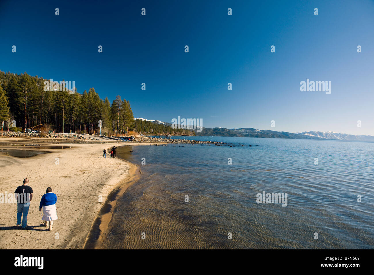 Un uomo e una donna a piedi lungo la spiaggia di Kings Beach Stato Area Ricreativa del Lago Tahoe California Foto Stock
