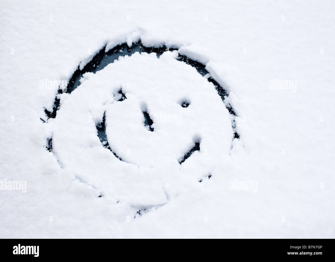 Smiley face disegnato in neve fresca su di un parabrezza di automobile Foto Stock