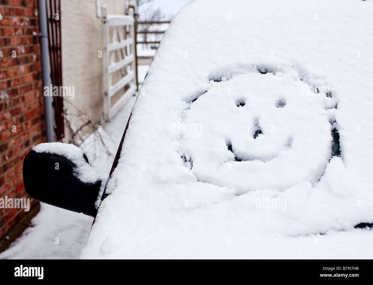 Smiley face disegnato in neve fresca su di un parabrezza di automobile Foto Stock