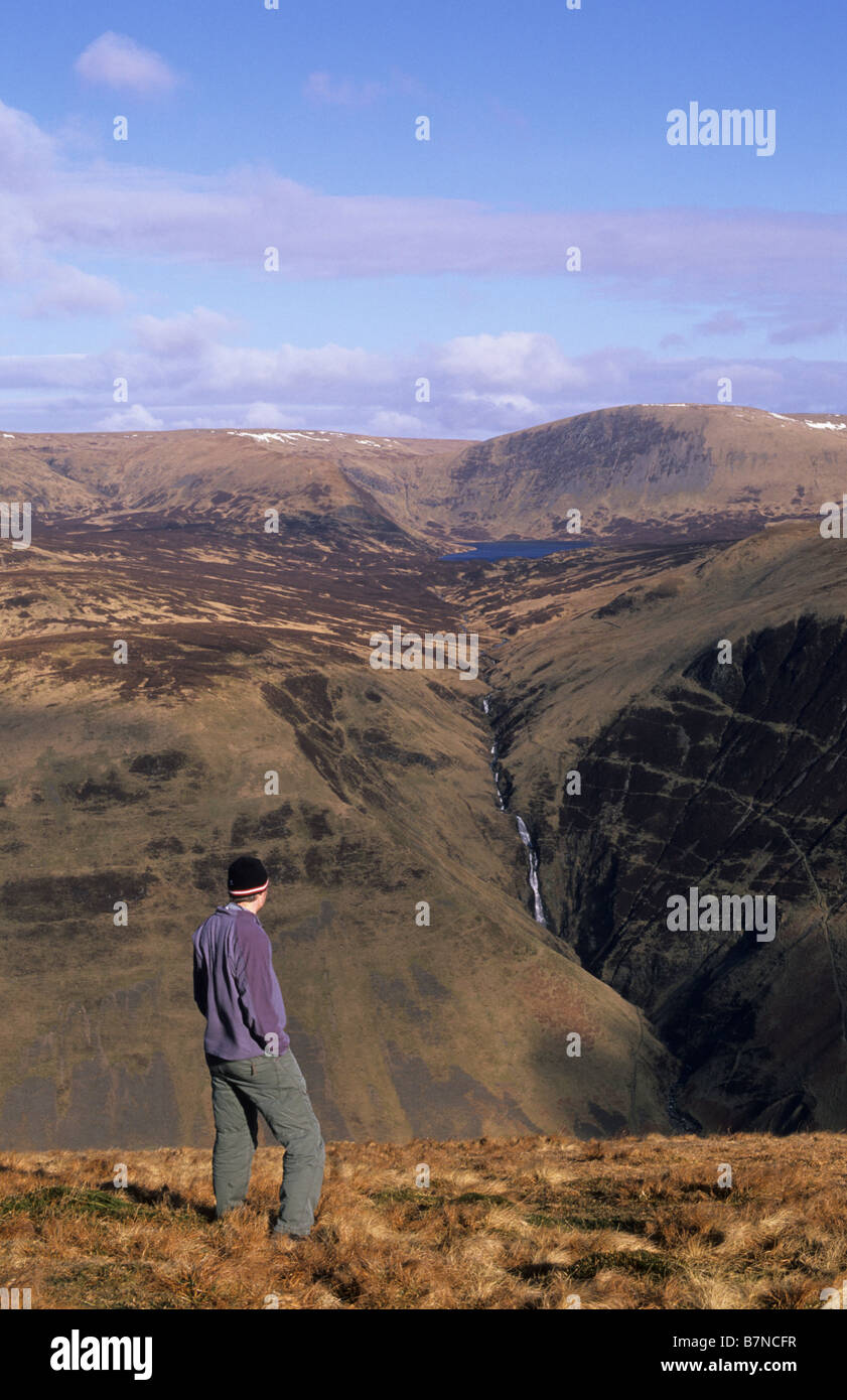Hillwalker guardando oltre al grigio mare di coda, Loch Skeen e testa Lochcraig, Moffatdale, Dumfries and Galloway, Scozia, l'inverno. Foto Stock