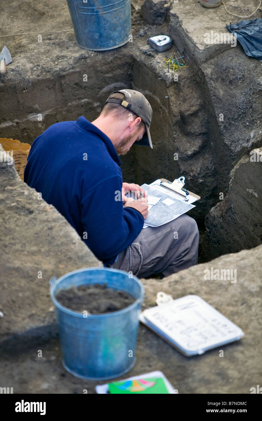 Archeologo informazioni di registrazione in un'Archeologia sito dig. Foto Stock