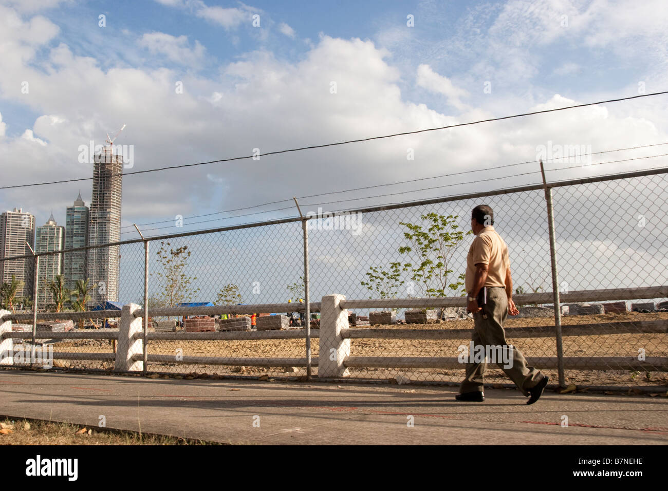 Un uomo cammina nella parte anteriore della circonvallazione costiera sito in costruzione. Balboa Avenue, Città di Panama, Repubblica di Panama, America Centrale Foto Stock