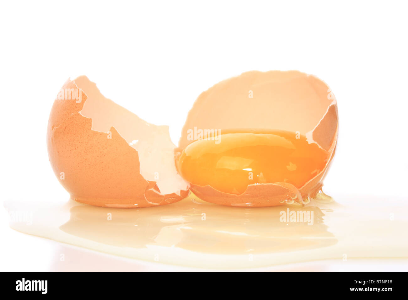 Un uovo rotto con tuorlo d'uovo isolato su bianco Foto Stock