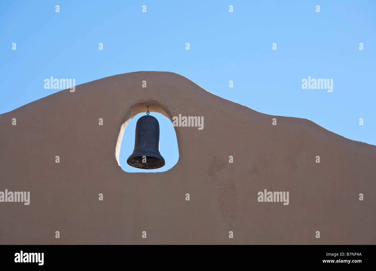 Vecchia campana Spagnolo su una tradizionale adobe parete edilizia Foto Stock