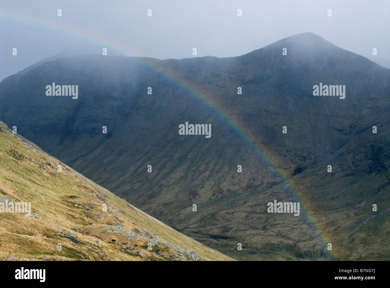 Rainbow in Lairig Gartain come tempesta di neve passa sopra Buachaille Etive Mor ridge, Glen Coe, Lochaber, Scozia, può Foto Stock