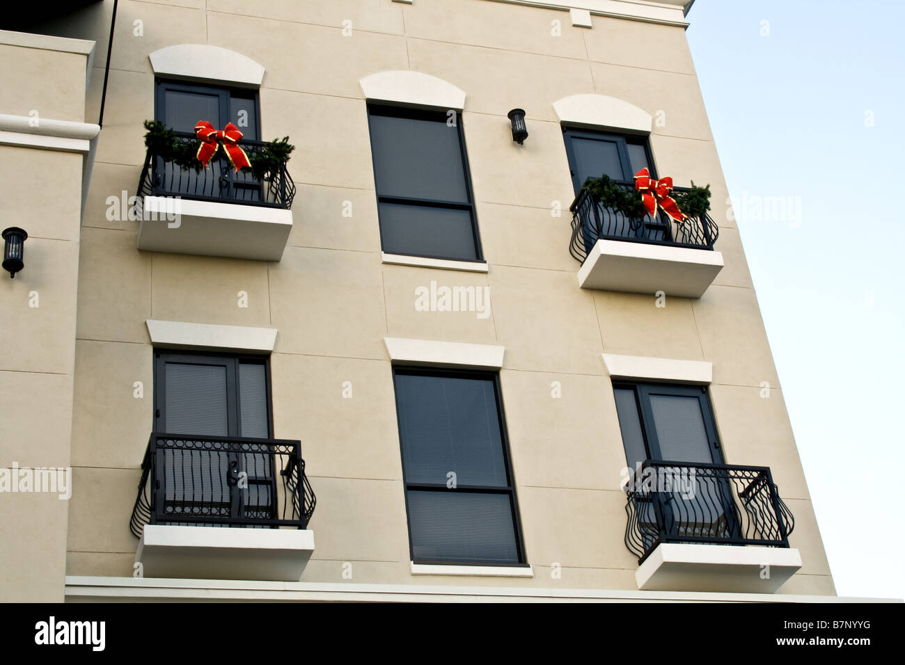 Windows in alto su un edificio decorato con Natale ghirlande e nastri montati su balconi in metallo Foto Stock