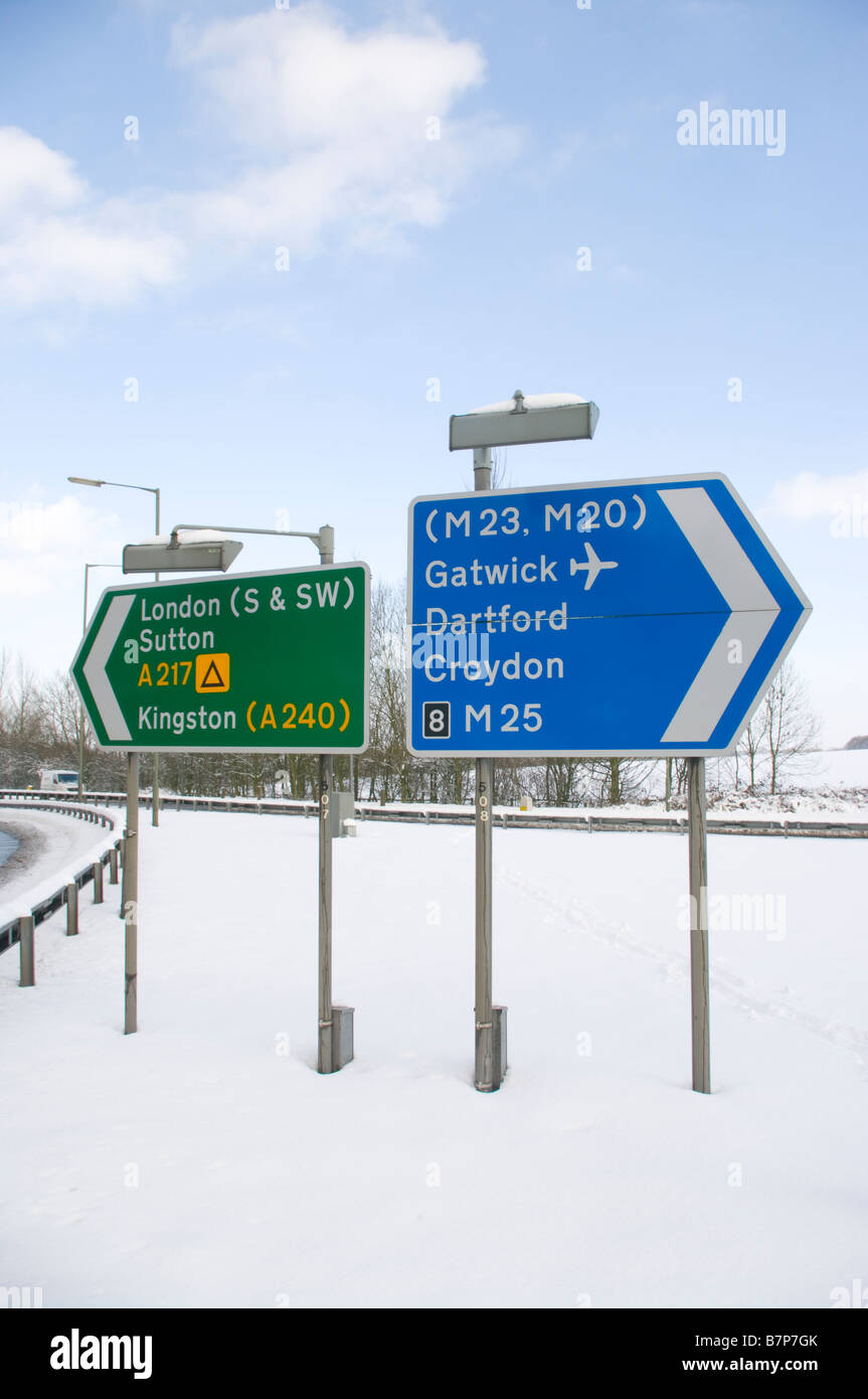 Nel regno unito il traffico su strada segno segni cartelli nella neve al Junction 8 M25 A217 Foto Stock