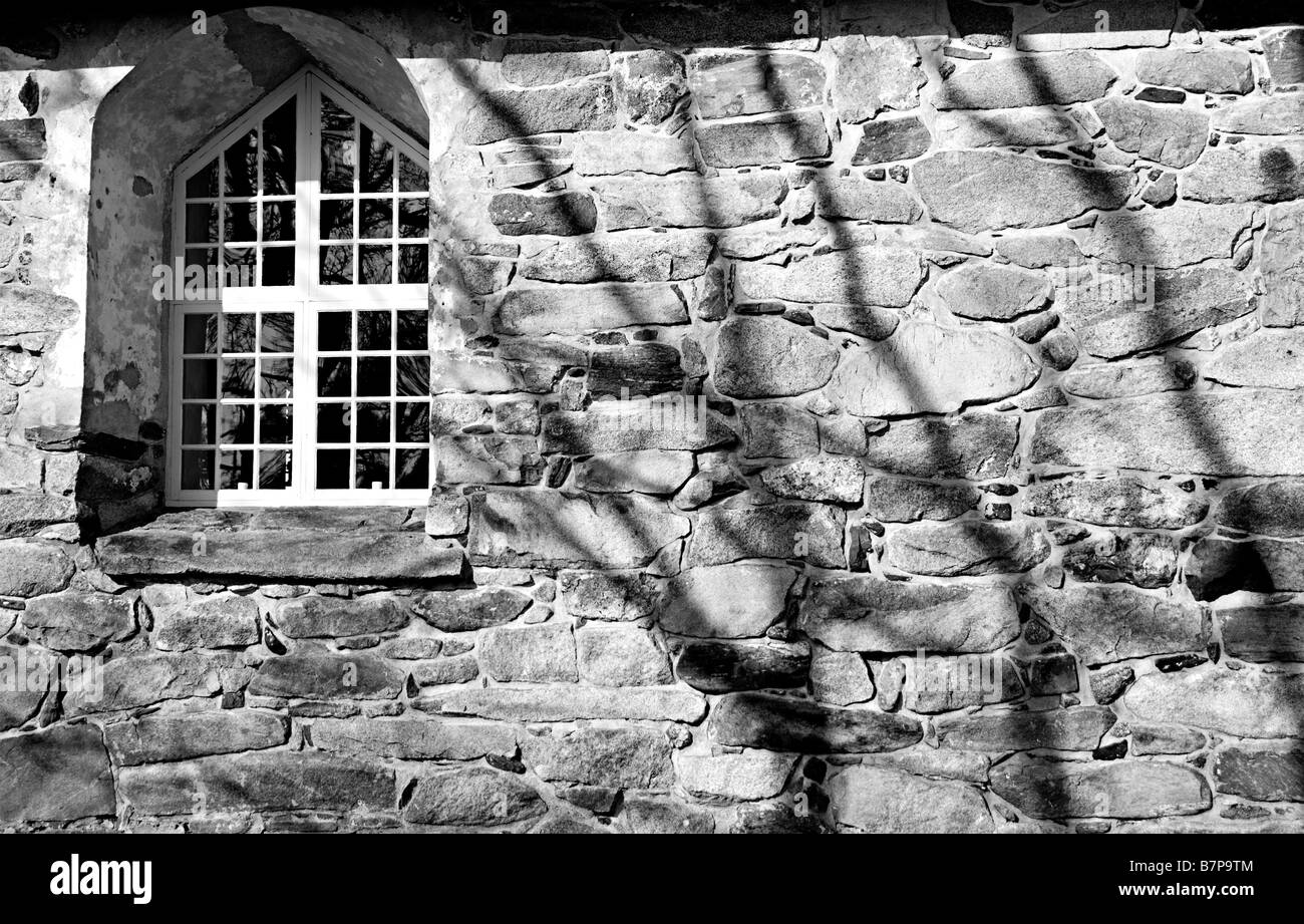 Vecchia chiesa di parete con finestra e le ombre degli alberi Foto Stock
