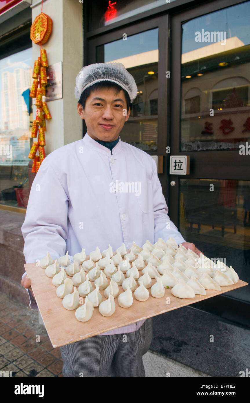 Un cuoco dal famoso gnocco Dongfang ristorante conserva un vassoio di carni fatte gnocchi Cinesi ad Harbin in Cina. Foto Stock