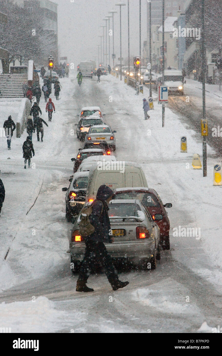 Linee di auto e pedoni lotta per salire una coperta di neve hill durante la mattina ora di punta dopo la neve pesante. Foto Stock