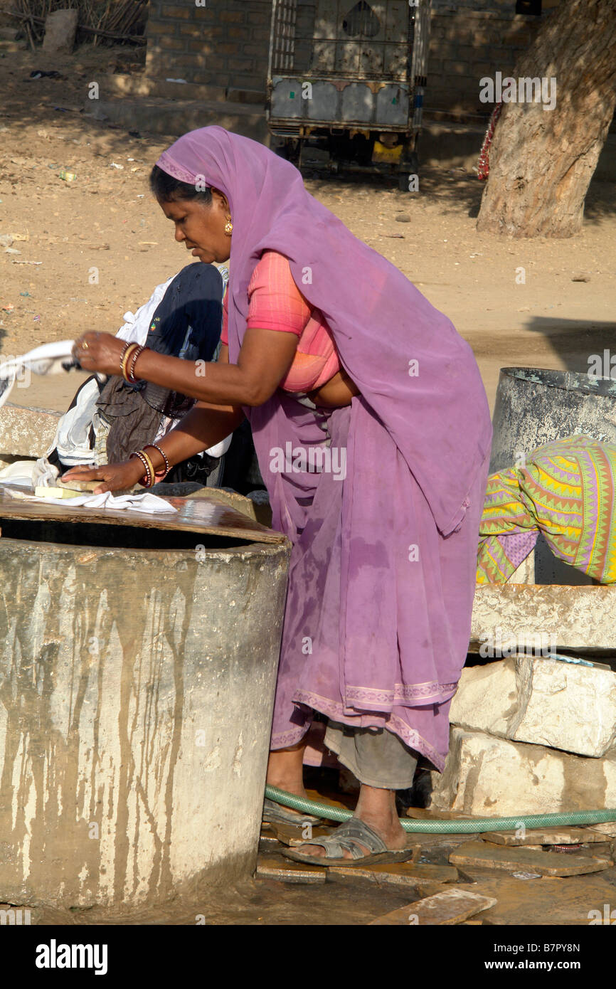 Donna indiana in abito tradizionale facendo il lavaggio esterno nelle stradine di jaisalmer vicino al fort Foto Stock