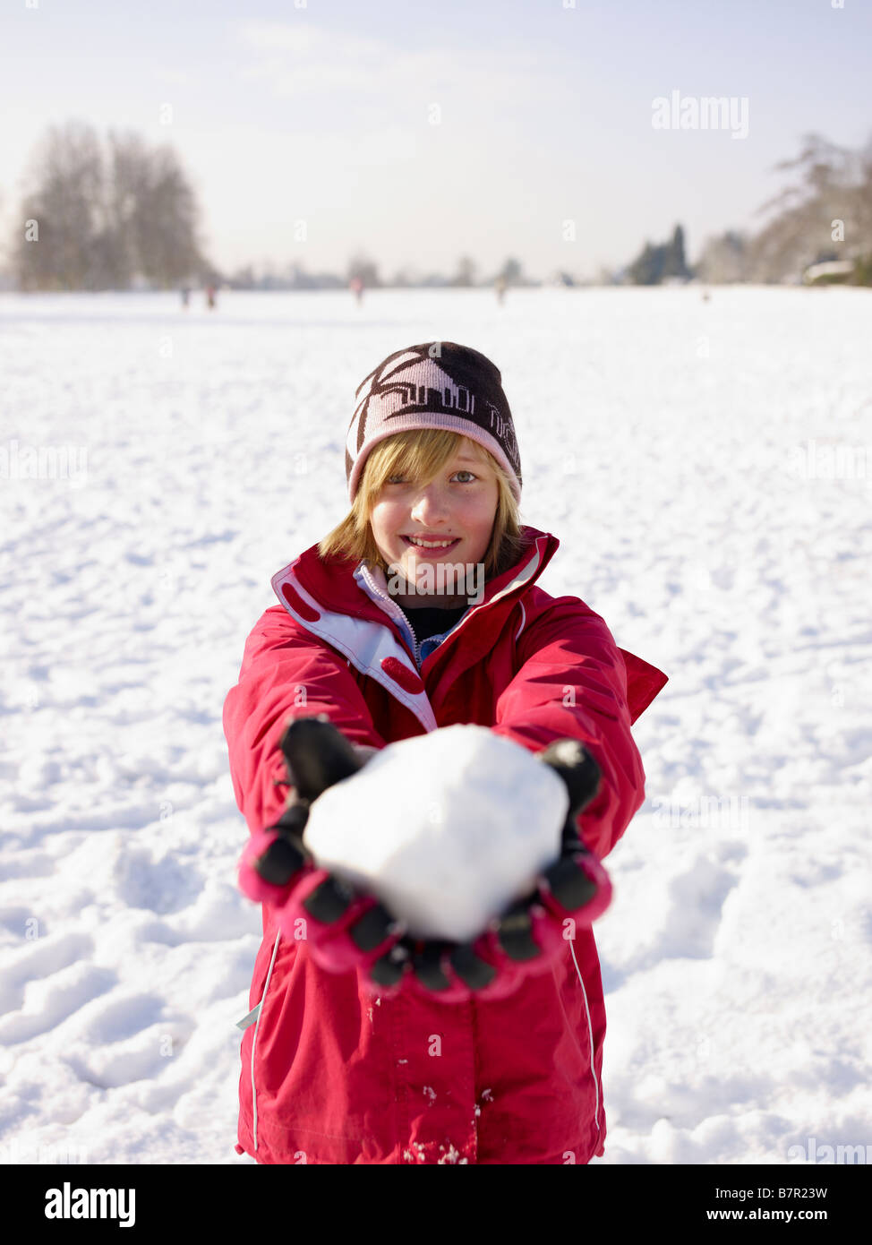 Ragazza con una palla di neve in una giornata nevosa Redbourn Hertfordshire Inghilterra REGNO UNITO Foto Stock