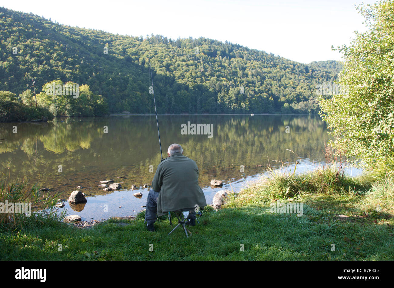 Pescatore con la linea sul bordo del lago Chambon in Auvergne. Francia Foto Stock