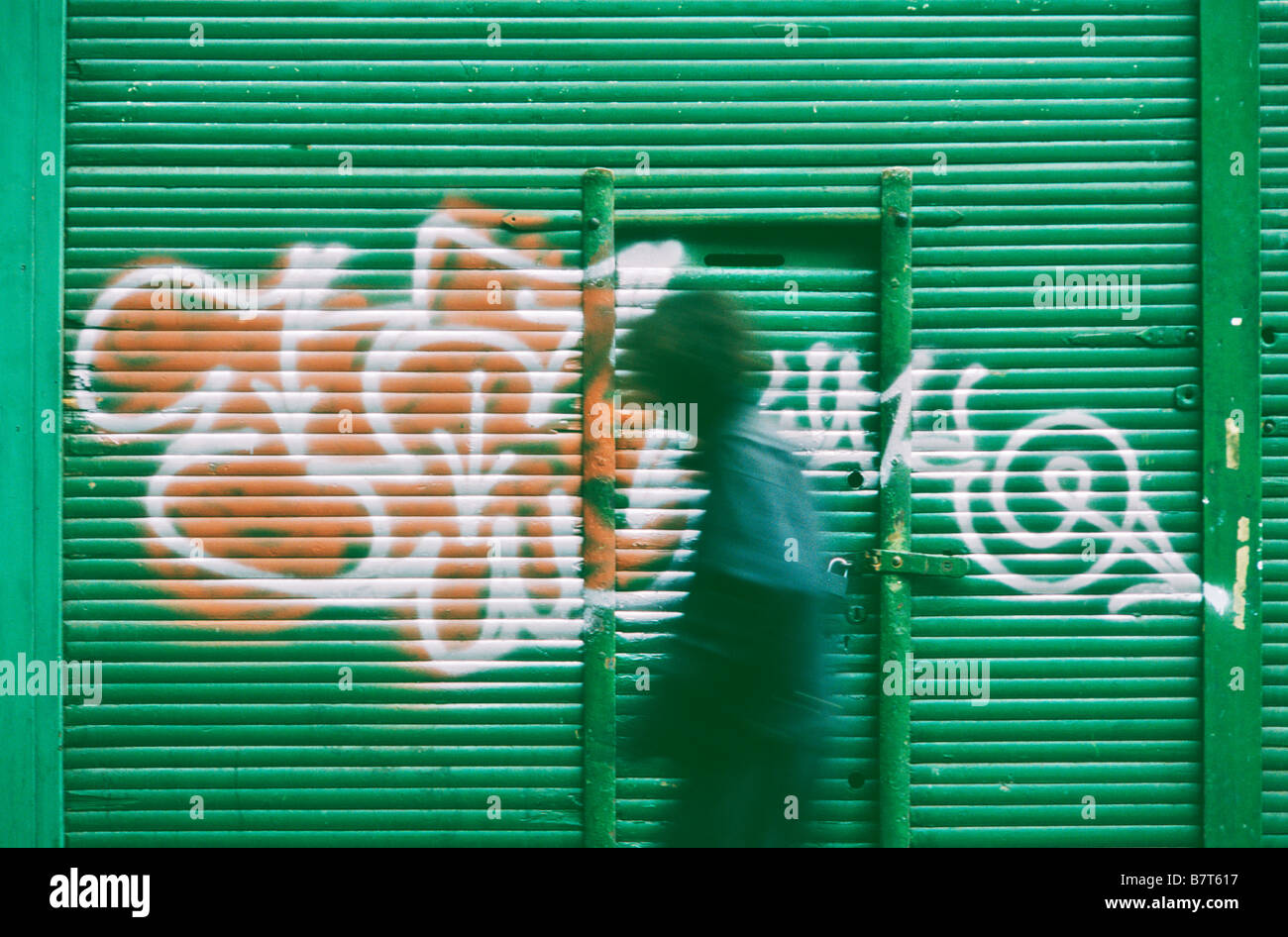La figura sfocata camminare davanti a un fondale di graffiti Foto Stock