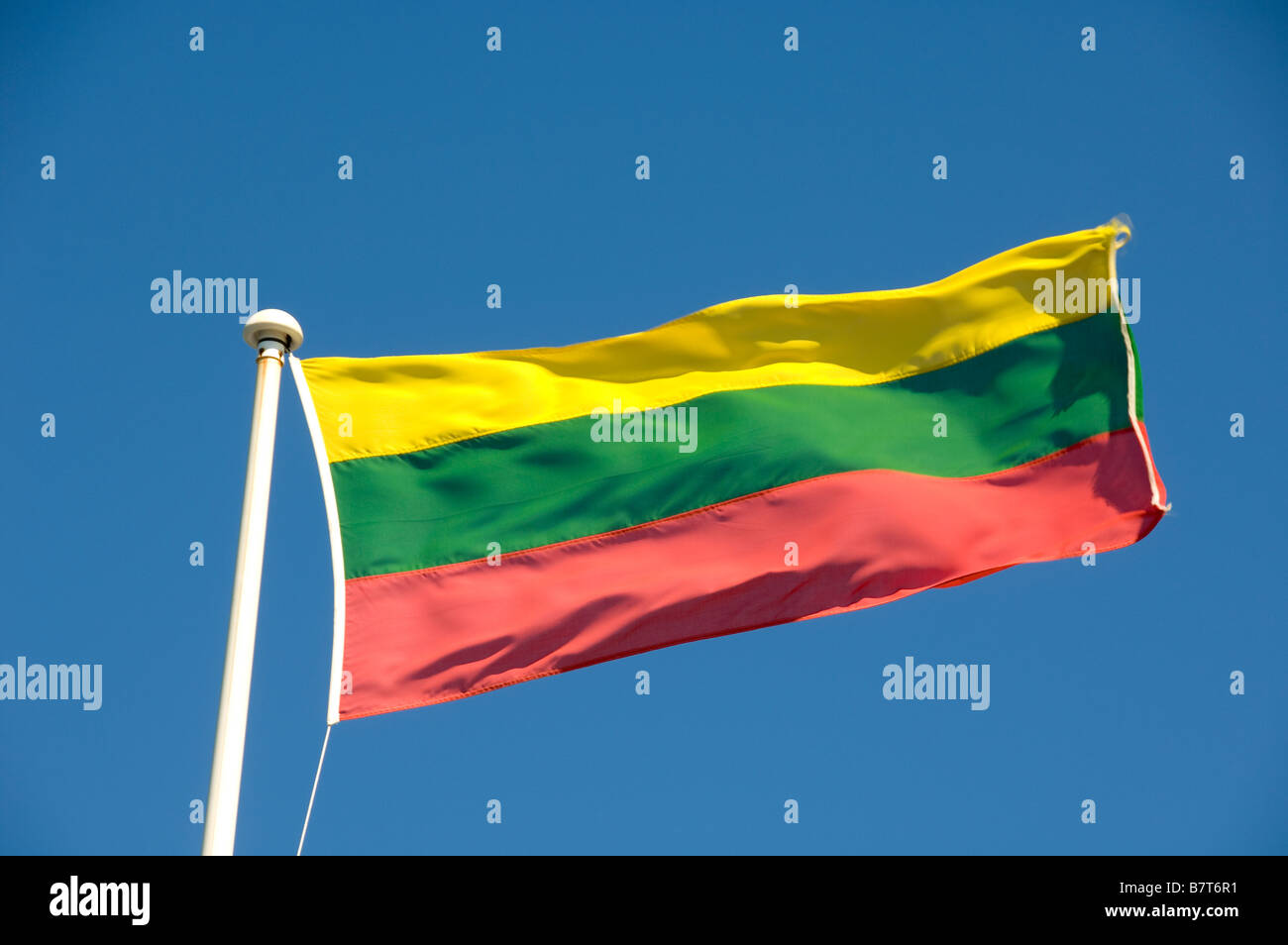 Bandiera lituana che vola su un palco bianco visto contro un cielo blu. Foto Stock