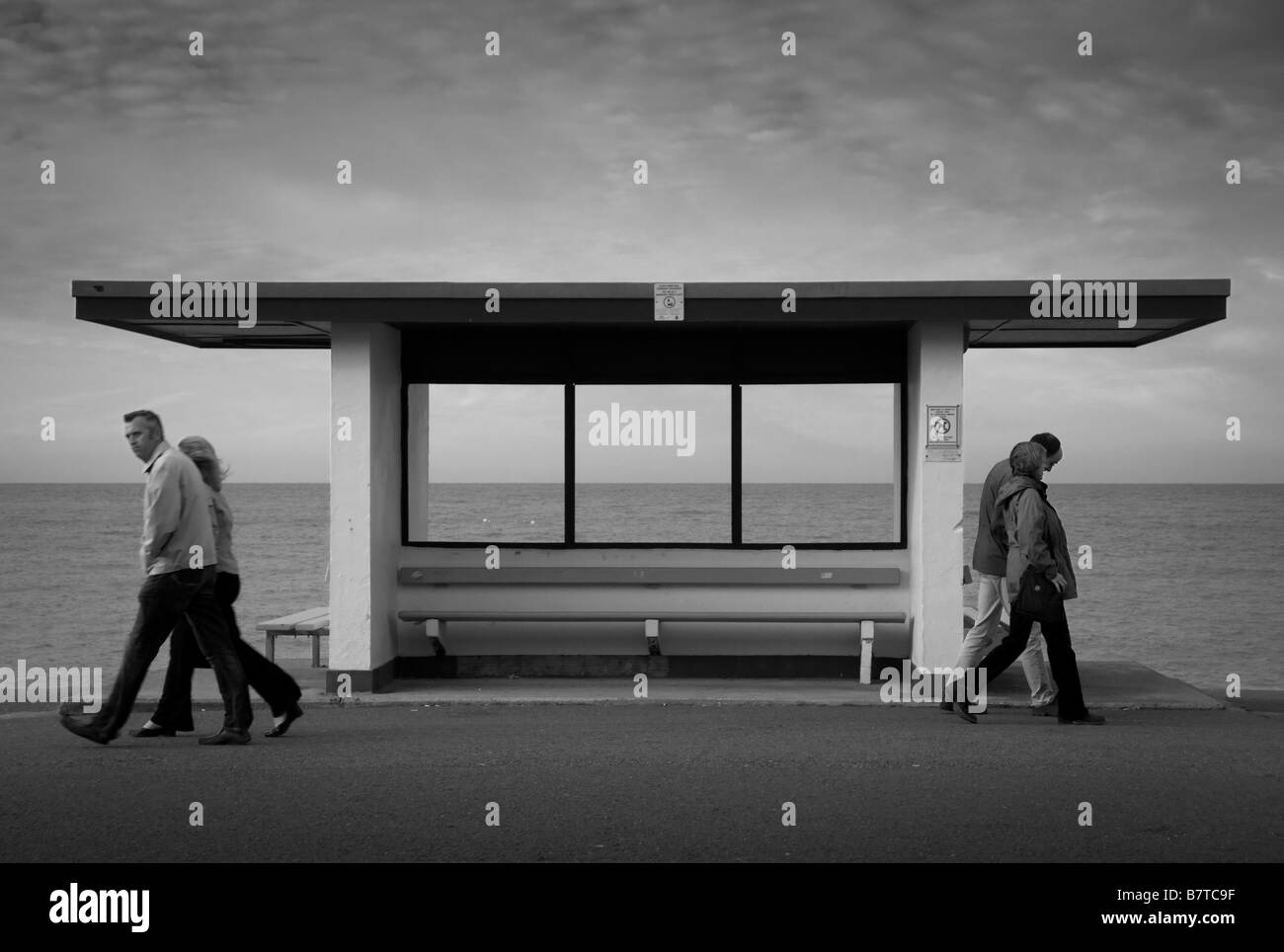 Bianco Brutalista mare rifugio con persone che passano sulla Llandudno Promenade con il mare in lontananza. Galles. REGNO UNITO. Foto Stock
