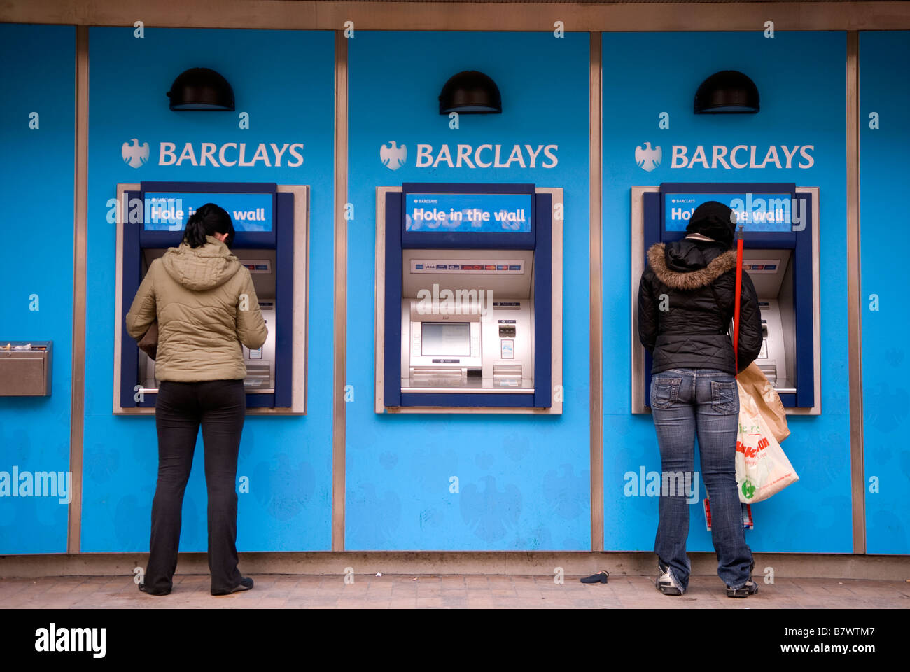 I clienti che utilizzano la Barclays Bank foro nella parete, High Street, Hounslow, Middlesex, Regno Unito. Foto Stock