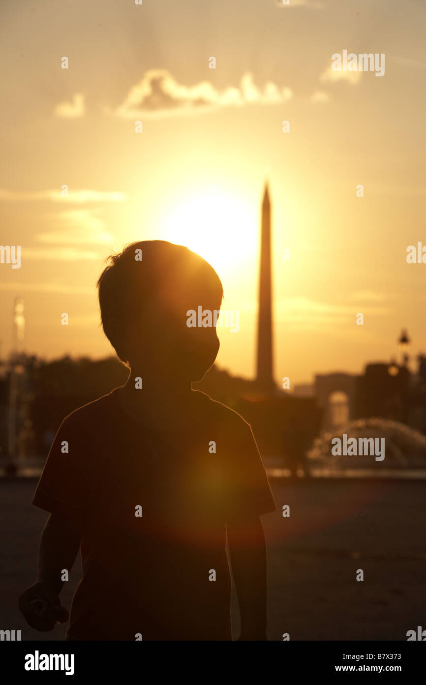 Silhouette di un giovane ragazzo godendo di un tramonto estivo al Jardin des Tuileries rivolta verso la Place de la Concorde, Paris, Francia Foto Stock