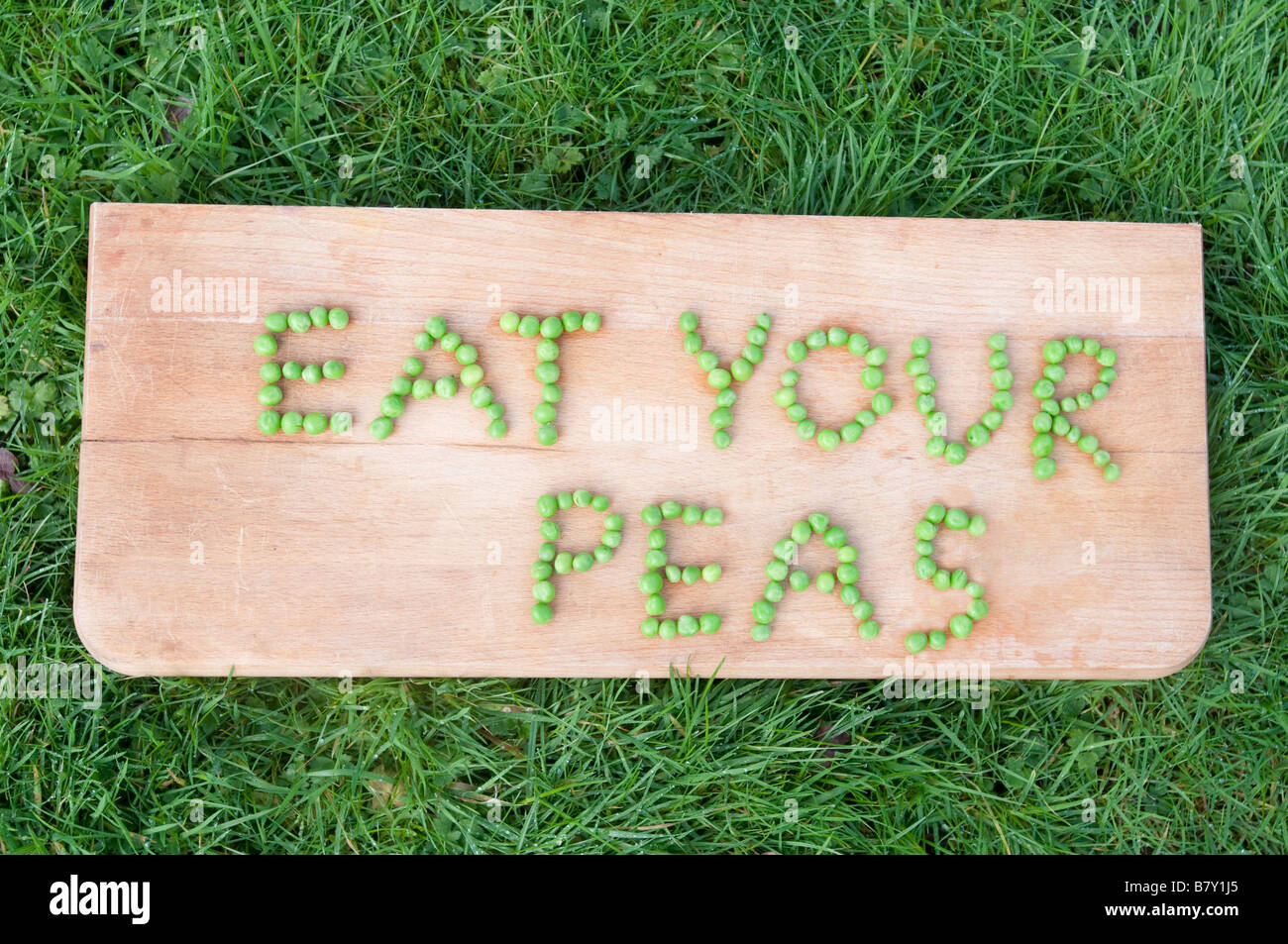 Mangiare i tuoi piselli precisate nei piselli su un blocco di trinciatura Foto Stock
