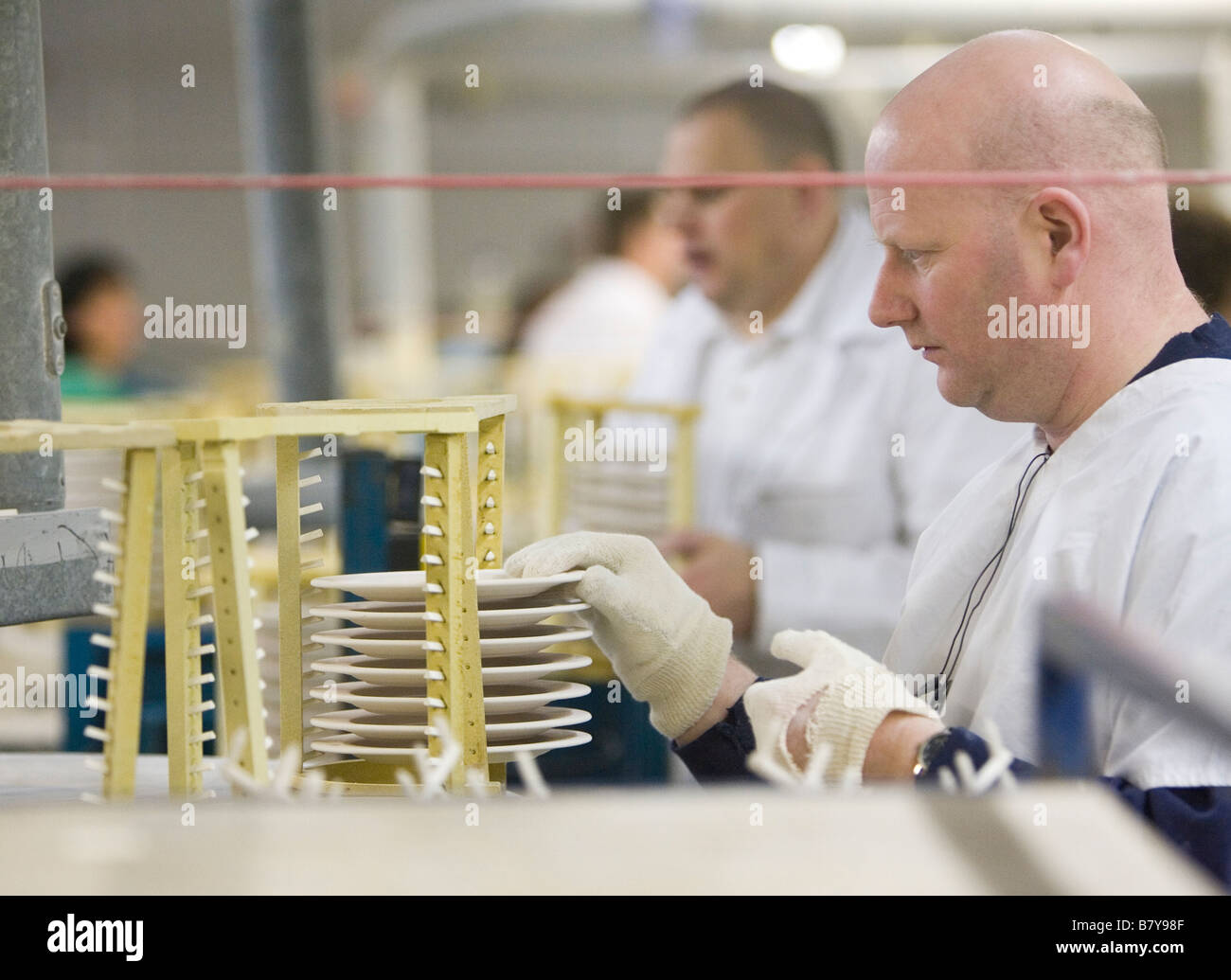 Un dipendente di Steelite International fabbrica di ceramiche a Stoke on Trent pone una piastra smaltata su un rack di asciugatura Foto Stock