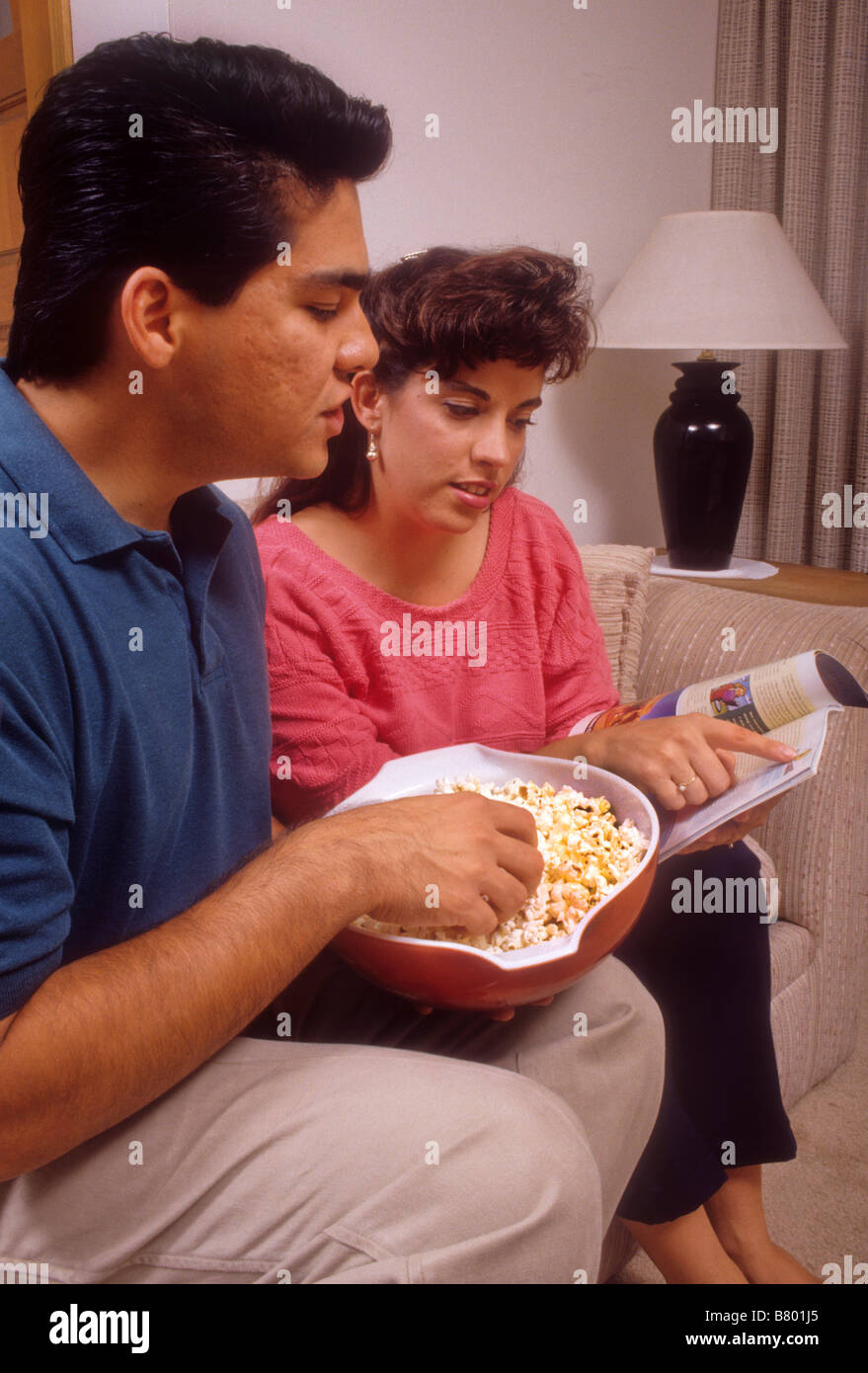 Ispanico giovane mangiare popcorn come studiano la guida TV Foto Stock