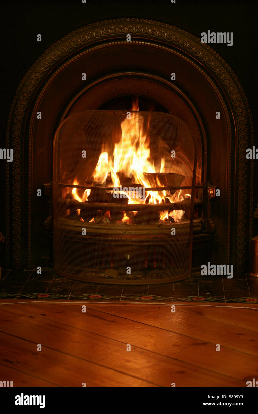 Una sostanziosa il fuoco di legna brucia luminoso, il riscaldamento della stanza vivente con un bagliore di benvenuto. Foto Stock