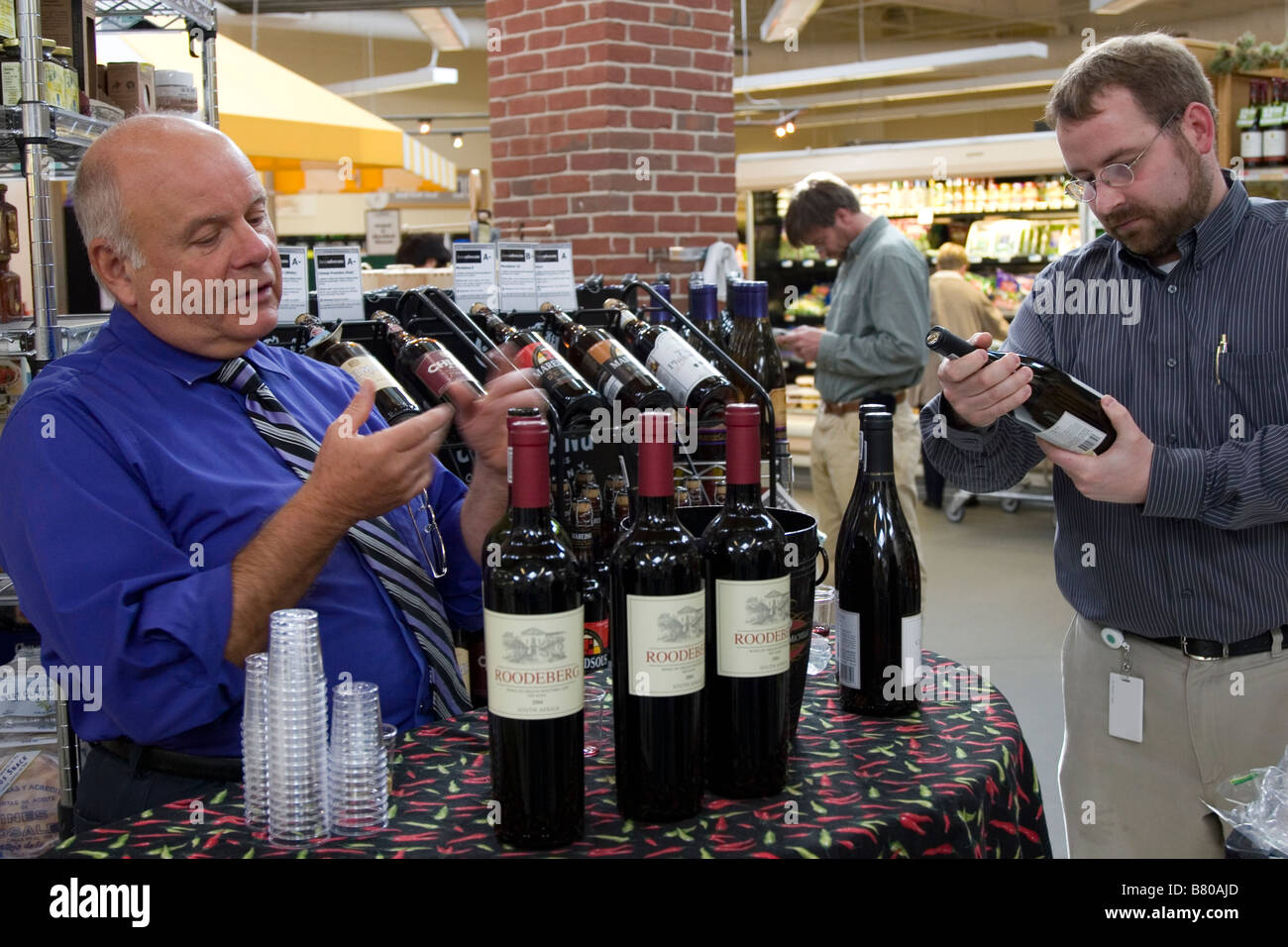 L'uomo offre gratuitamente i campioni di vino da un altro uomo nel negozio di alimentari Foto Stock