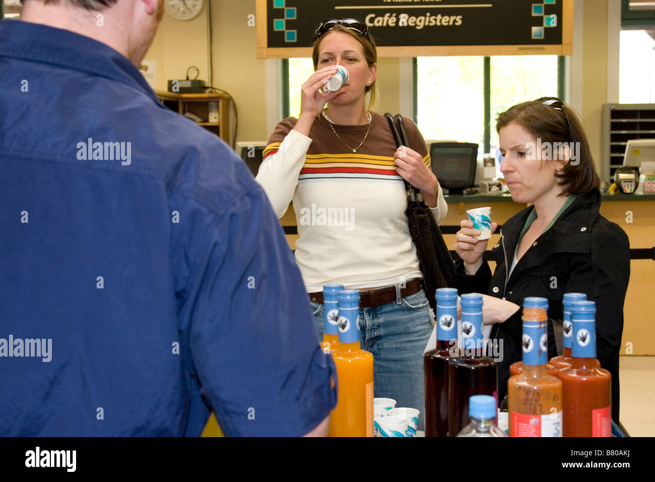 L'uomo offre gratuitamente i campioni di succo di due donne nel negozio di alimentari Foto Stock
