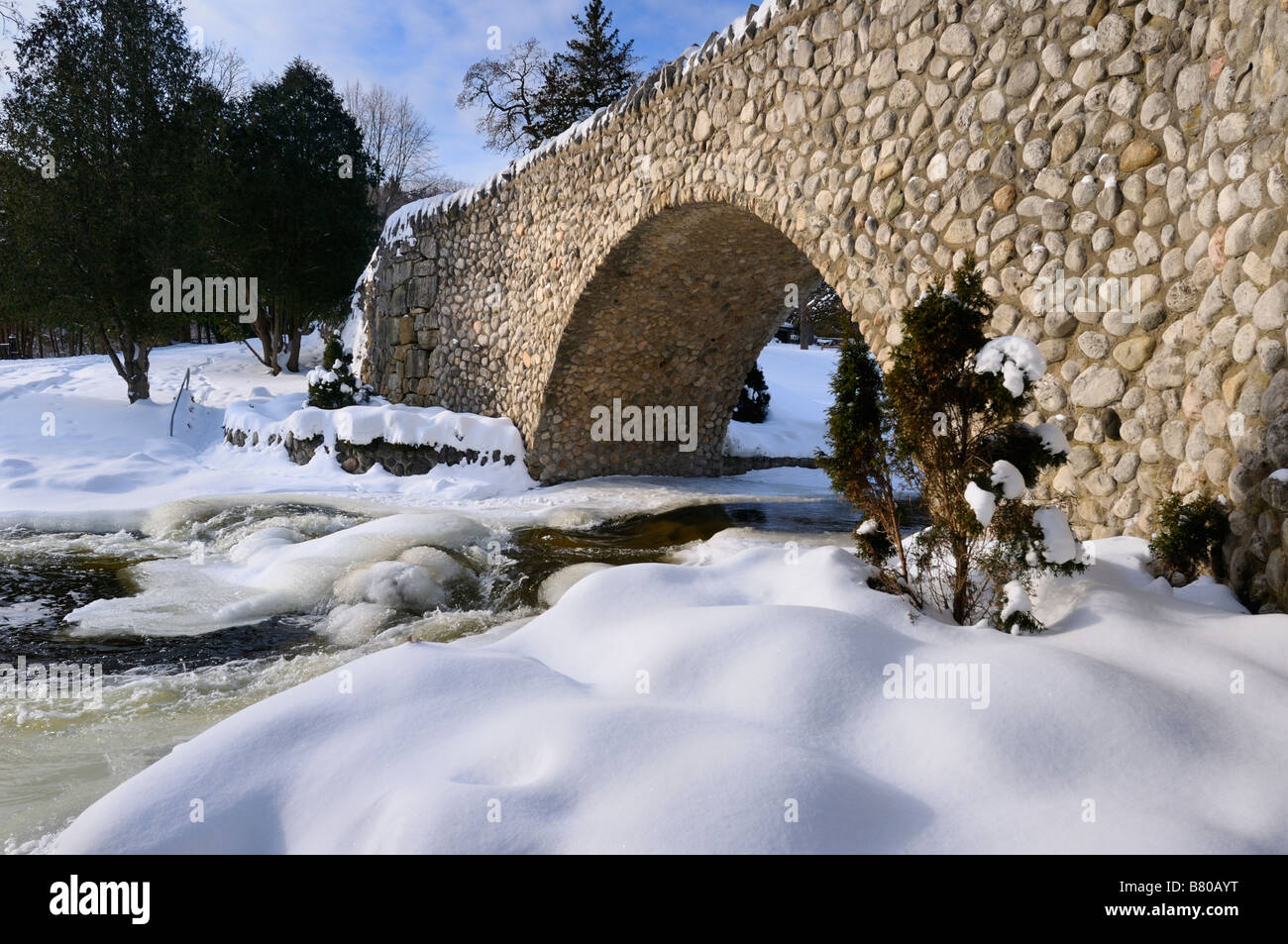 Spencer Creek in esecuzione sotto un ponte in pietra a Webster cade Conservation Area Parco in inverno Foto Stock
