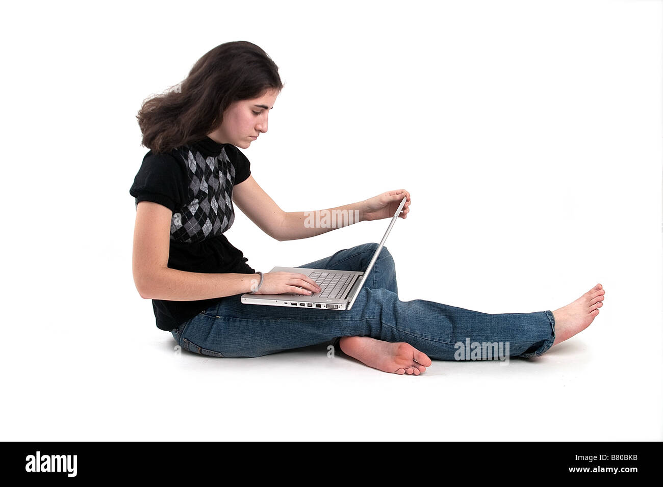 Un teenager di età ragazza seduta sul pavimento usando il suo computer portatile Foto Stock
