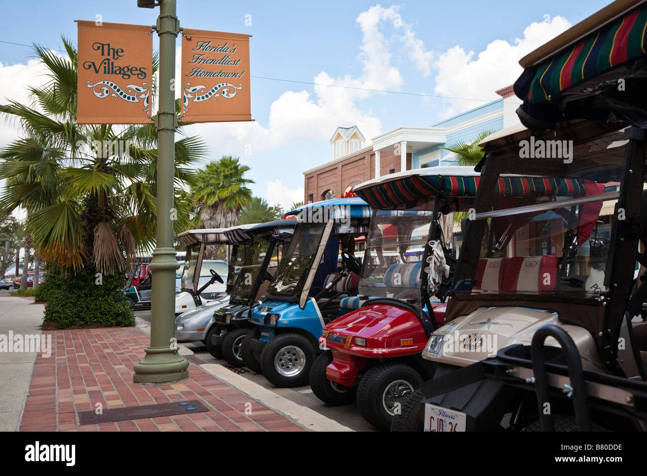 Carrelli da golf parcheggiate lungo la strada principale nei villaggi la comunità di pensione nella Florida Centrale, STATI UNITI D'AMERICA Foto Stock