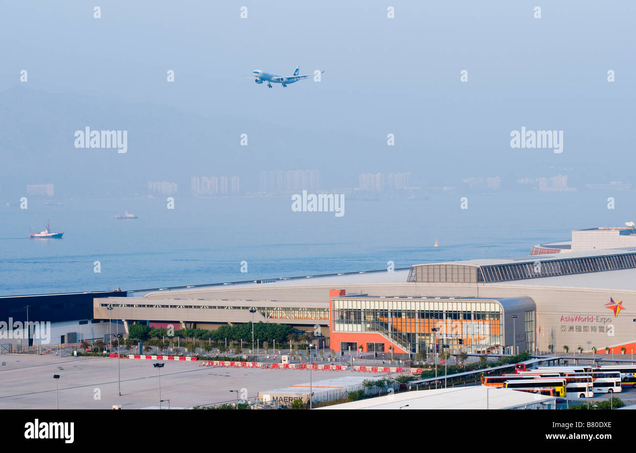 Un aereo arriva a Hong Kong Chek Lap Kok Airport accanto all'Asia World Expo di Hong Kong Foto Stock