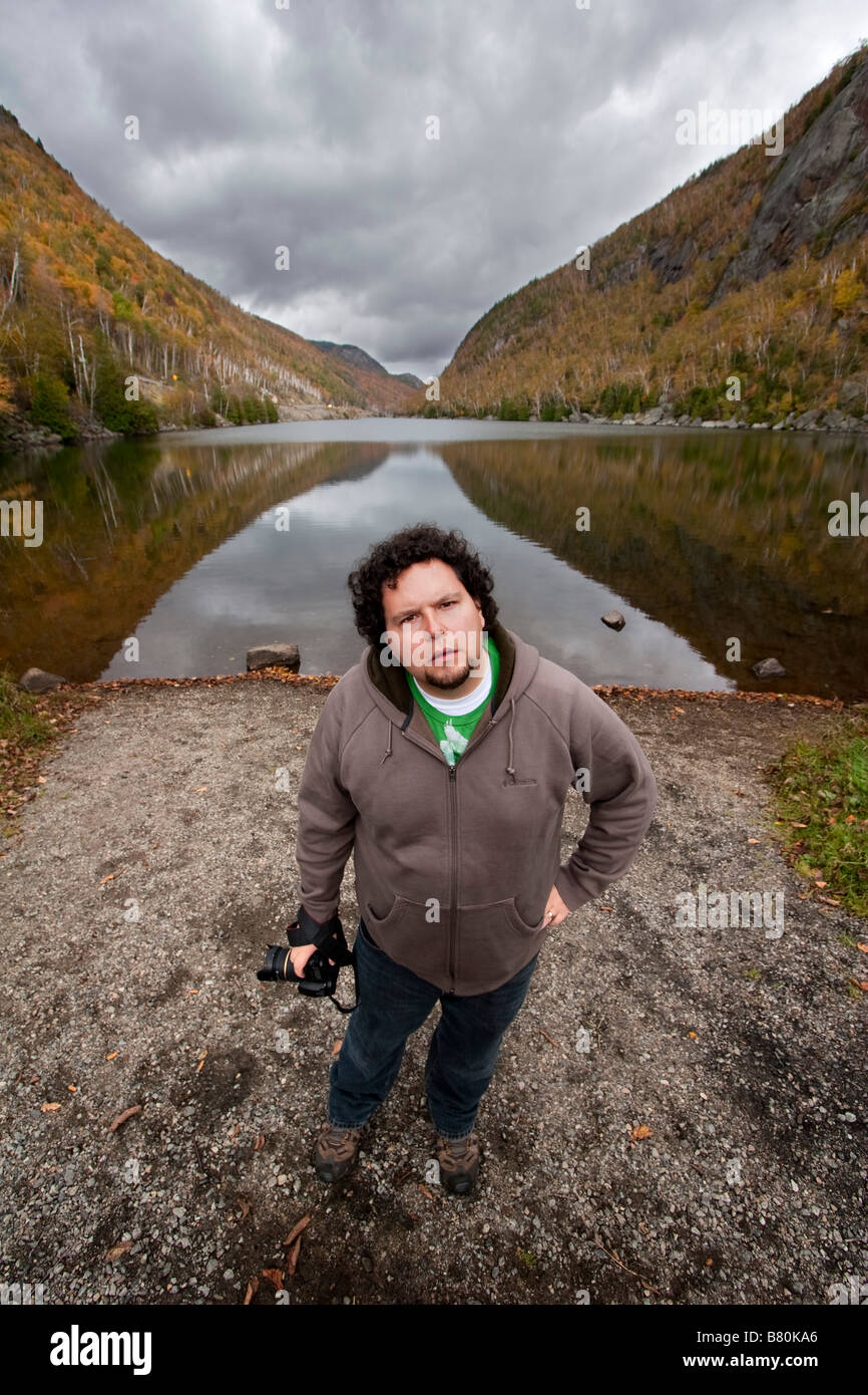 Un uomo con una telecamera in piedi di fronte ad un lago degli Adirondacks di New York il 6 ottobre 2008 il signor sì Foto Stock
