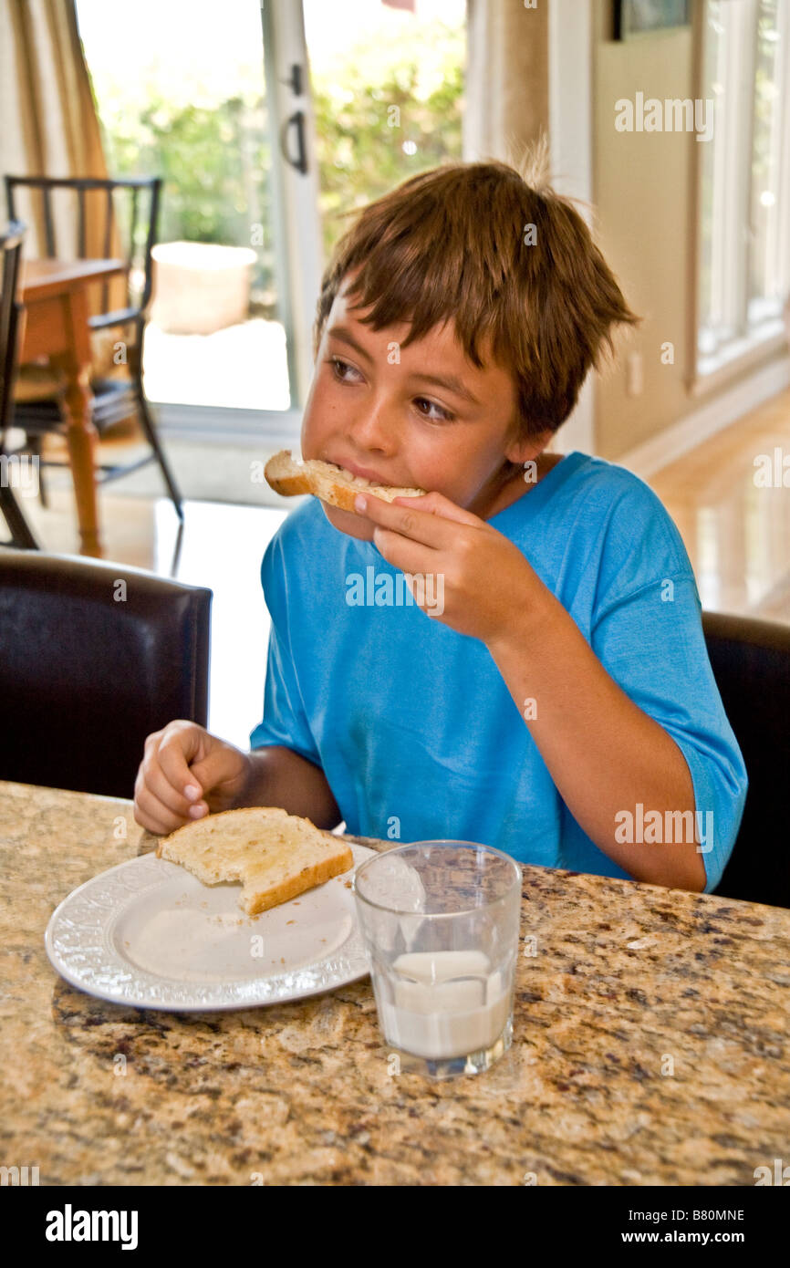 A dieci anni di vecchio ragazzo mangia la sua colazione a base di pane tostato e latte a casa in Laguna Niguel CA Foto Stock