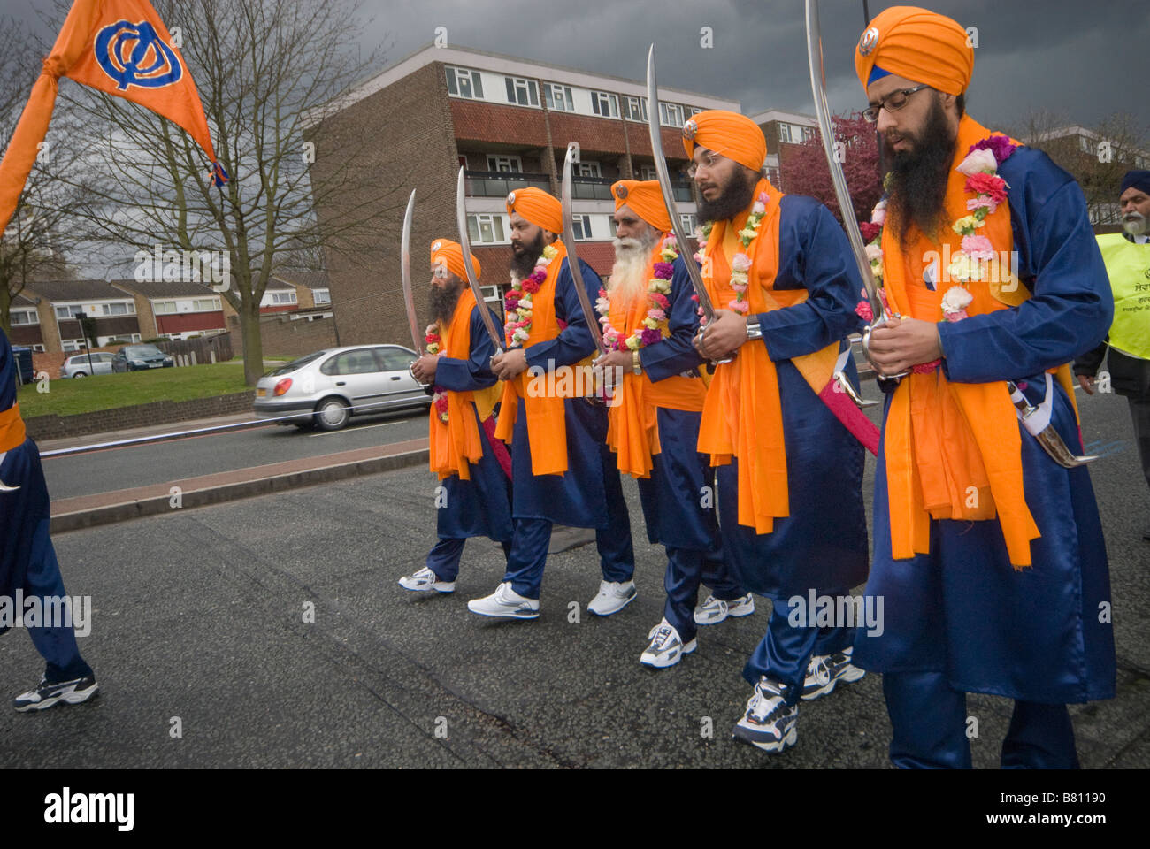 Il 'amato cinque " (Panj Piare) a piedi con le spade sollevate dietro la bandiera Sikh alla testa della processione Vaisakhi a Woolwich Foto Stock
