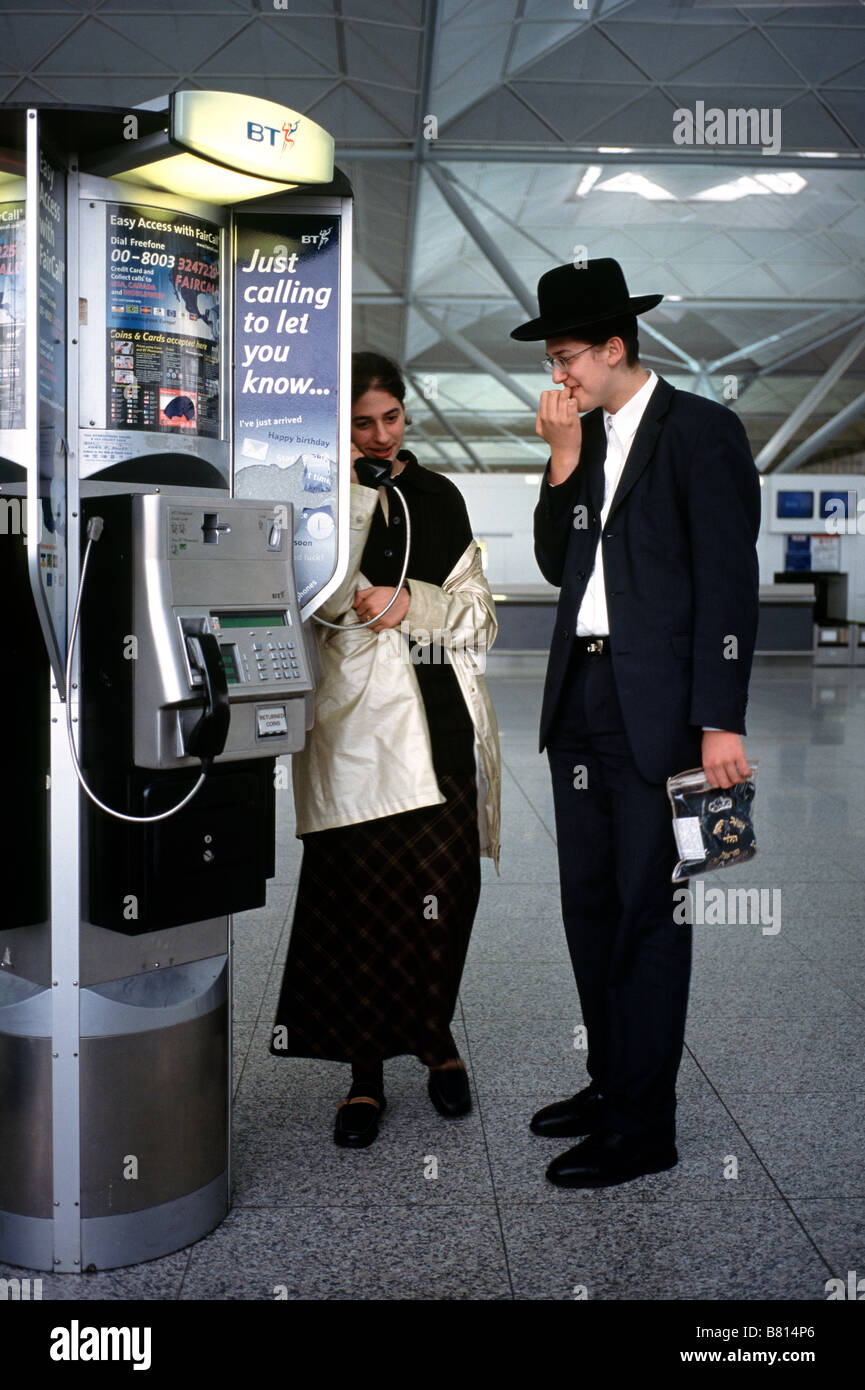 Ott 7, 2003 - ebrei ortodossi di chiamare a casa da un pubblico BT publifon dentro l'aeroporto di Stansted la sala partenze. Foto Stock