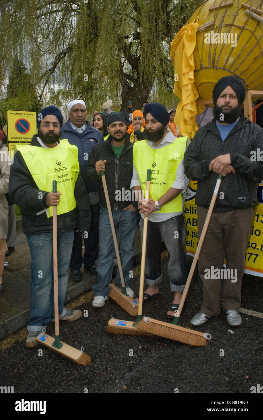 Gli uomini con scope per spazzare il percorso nella parte anteriore del Panj Piare e Guru Granth Sahib per Woolwich Vaisakhi processione, Aprile 2008 Foto Stock