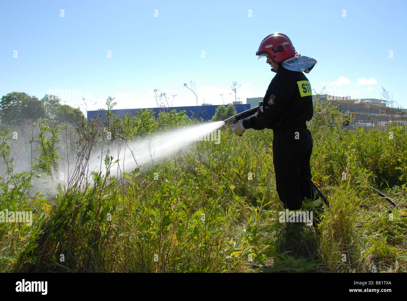 Vigili del fuoco usando un tubo flessibile a getto di aspo su un fuoco heath Foto Stock