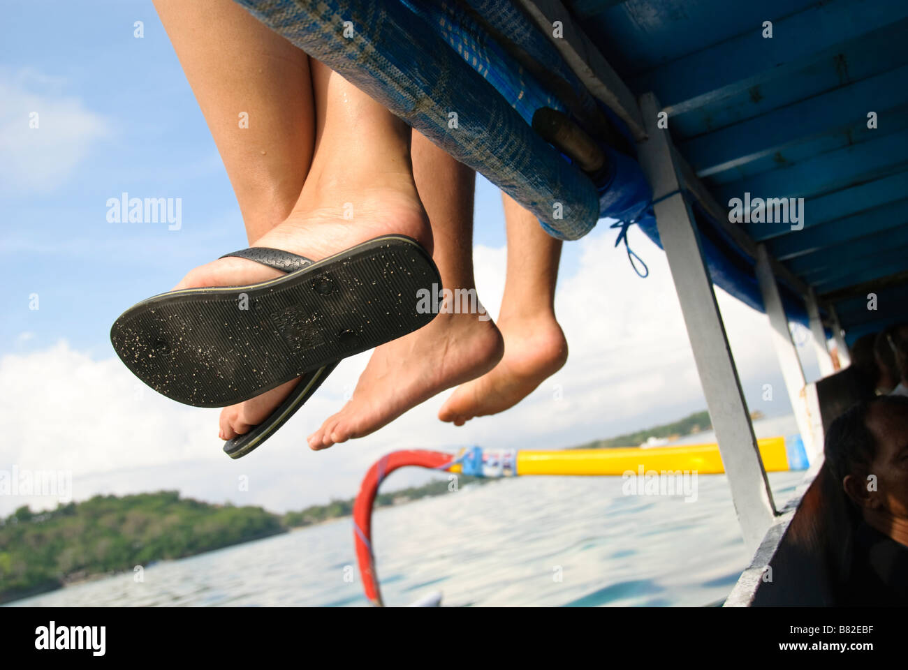 Piedi dangled off ponte superiore di una barca lasciando Nusa Lembongan, Bali, Indonesia Foto Stock
