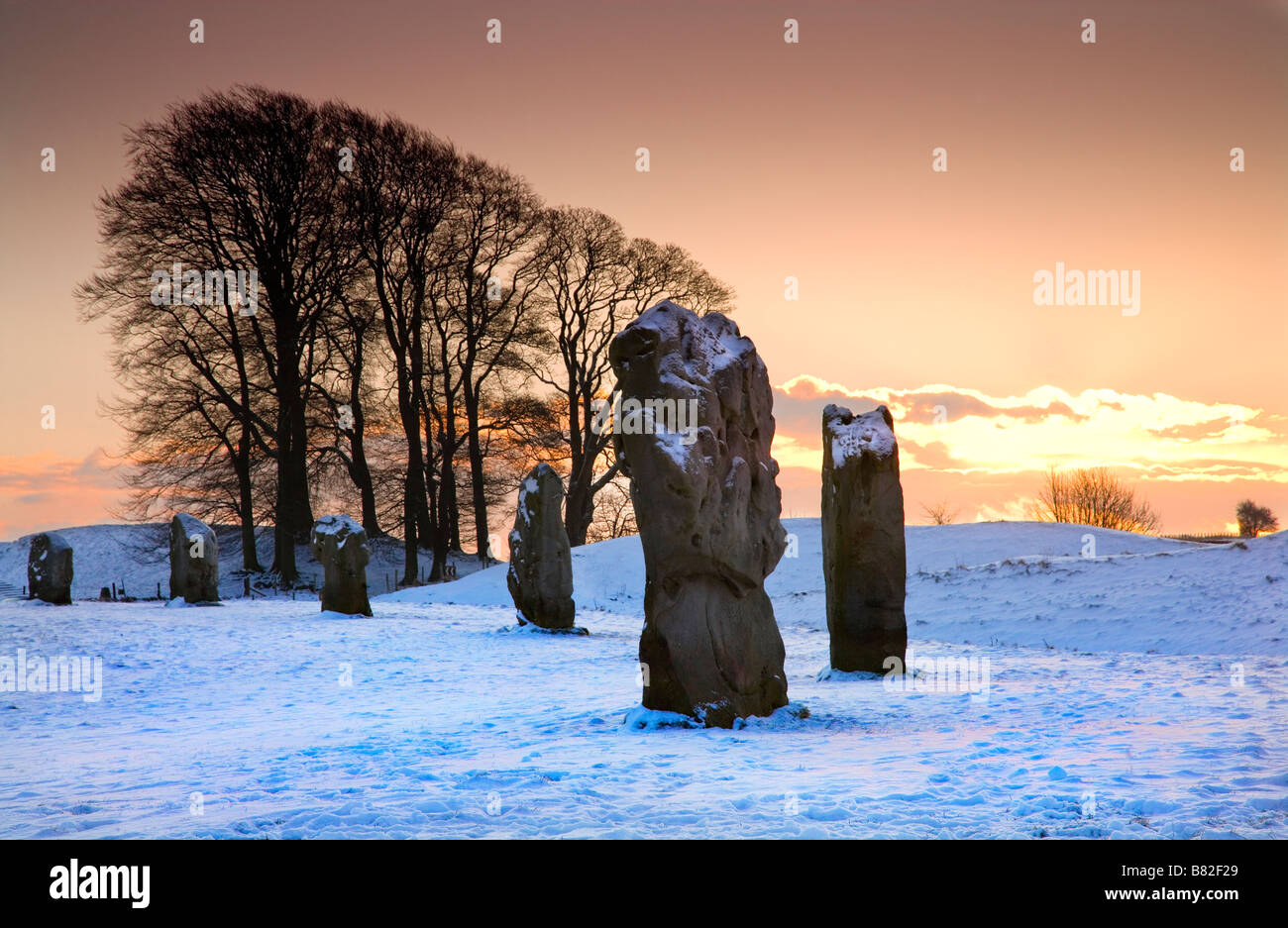 Un inverno nevoso tramonto sull'sarsen le pietre a Avebury nel Wiltshire, Inghilterra REGNO UNITO Foto Stock