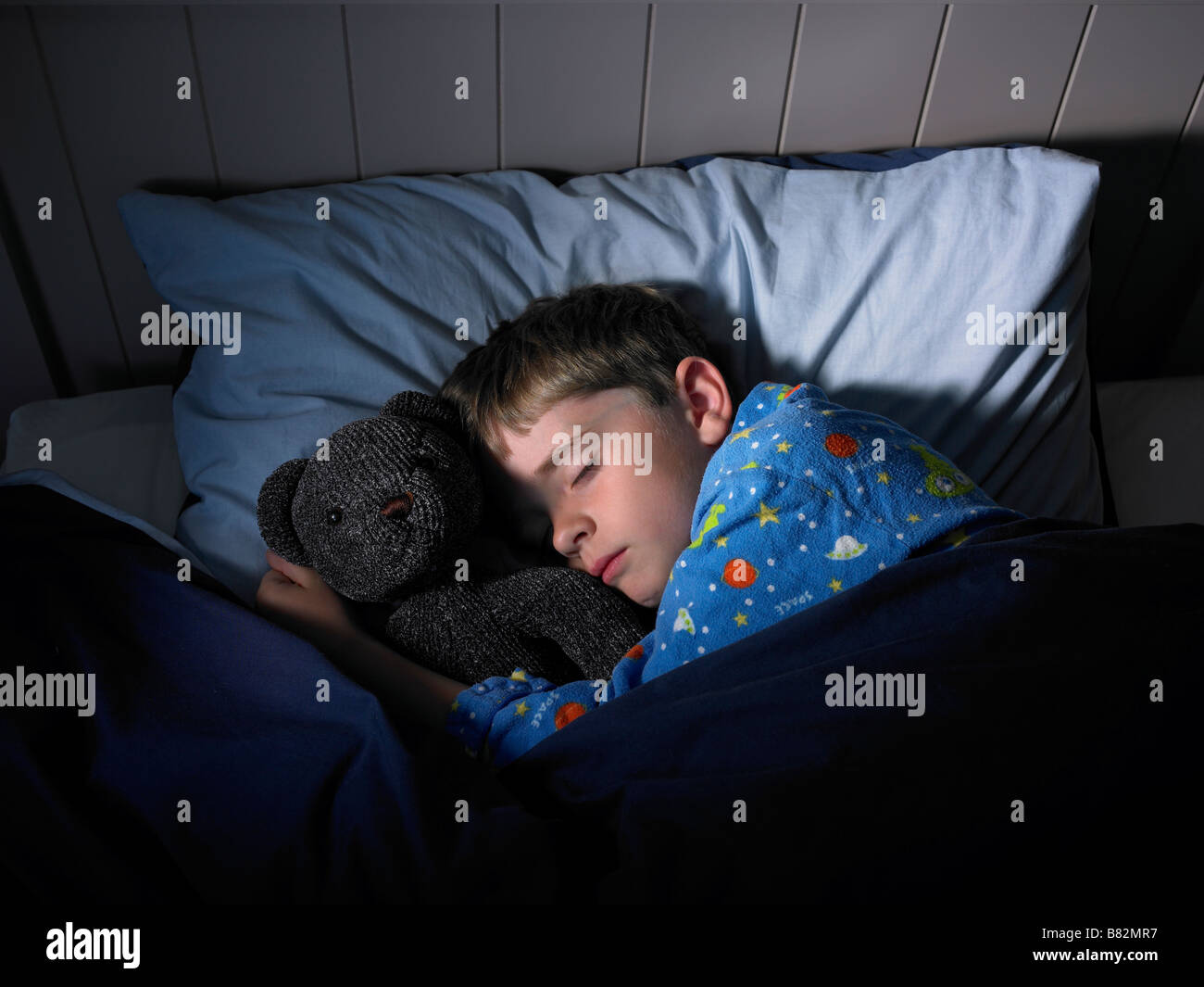 Un giovane bambino dorme con il suo orsacchiotto di peluche Foto Stock