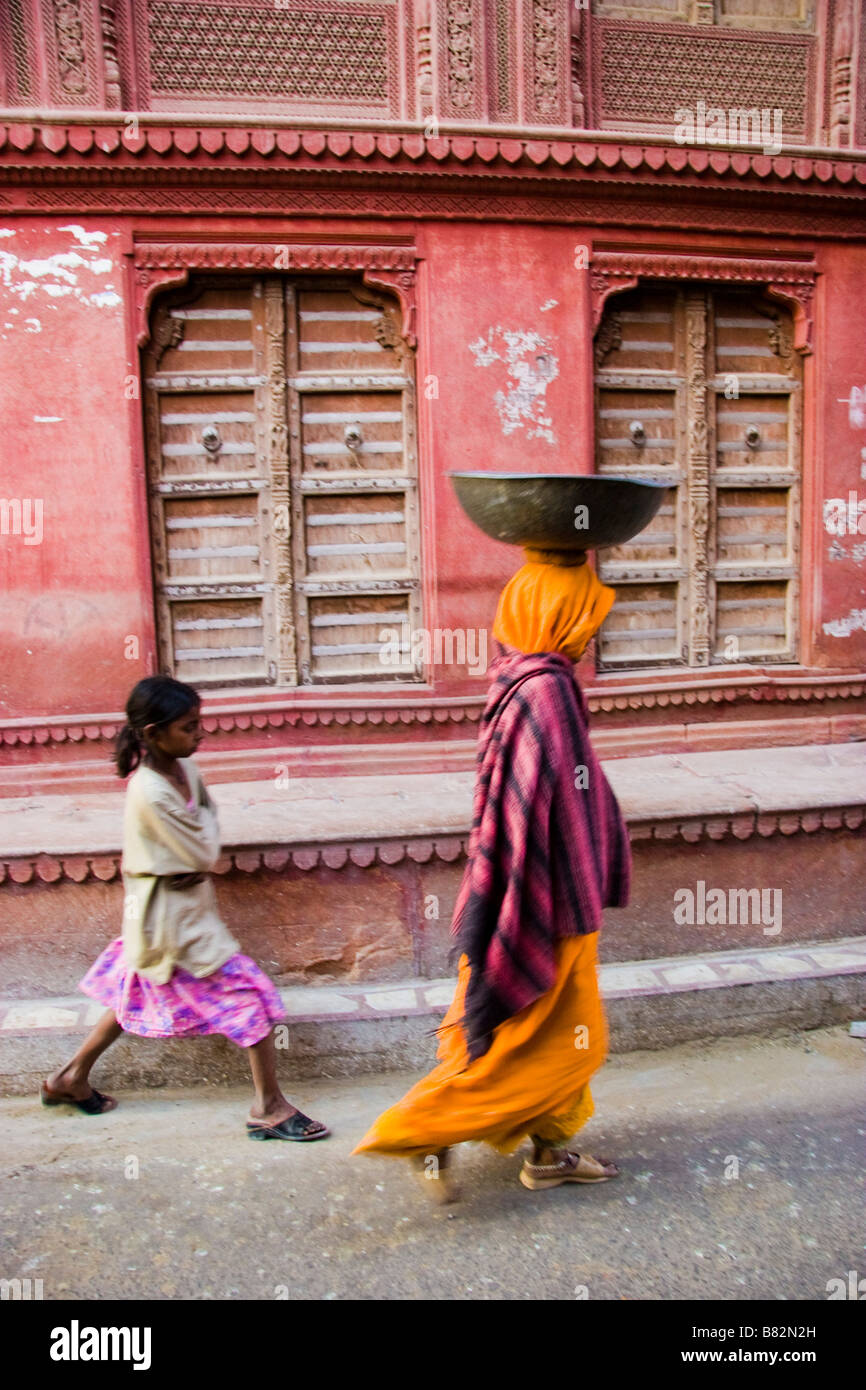 Donna e bambina a piedi passato esterno di un Haveli Bikaner Rajasthan in India Foto Stock