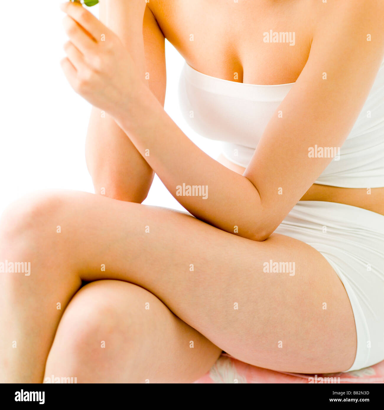 Giovane donna seduta gambe incrociate a ginocchio metà sezione Foto Stock