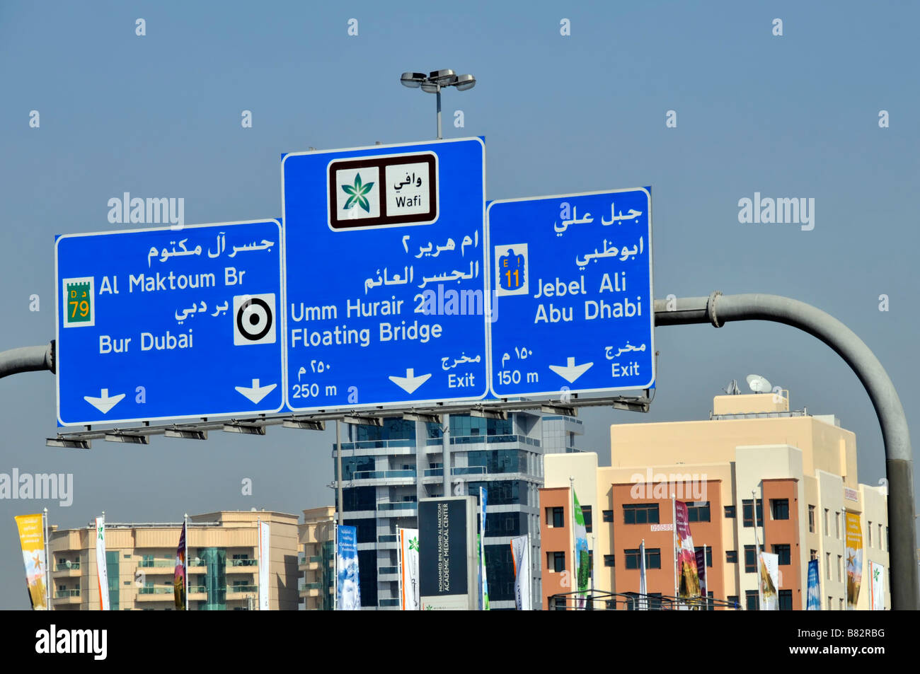 Dubai blu autostrada bilingue uscita uscita destinazione segnaletica percorso Gantry sopra il traffico paesaggio urbano soleggiato Emirati Arabi Uniti Emirati Arabi Uniti Medio Oriente Foto Stock